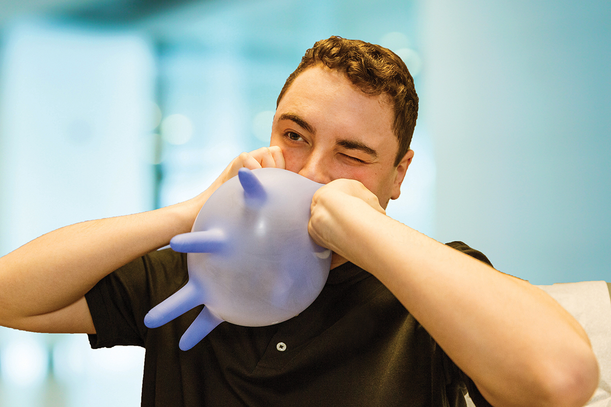 A boy blows up a glove like a balloon