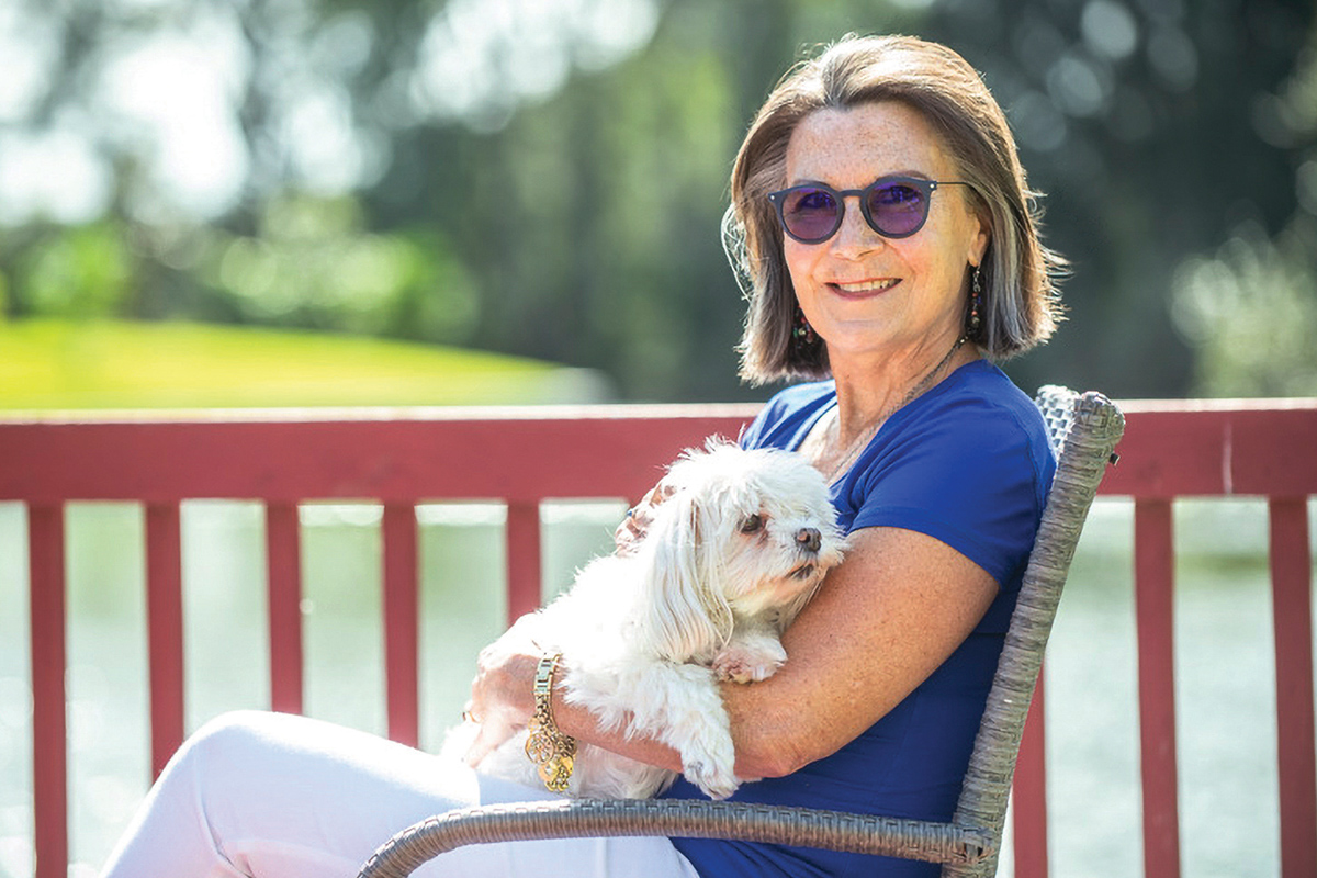 Woman sitting on a deck holding a dog