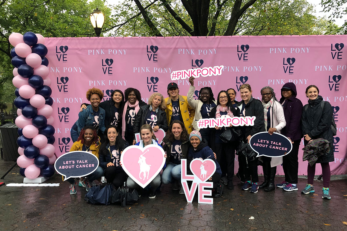 People gathered in front of a large pink banner that says Pink Pony Walk 2019