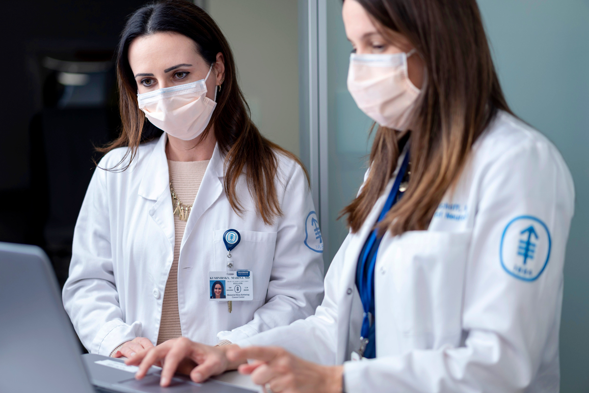 A doctor and trainee looking at a laptop