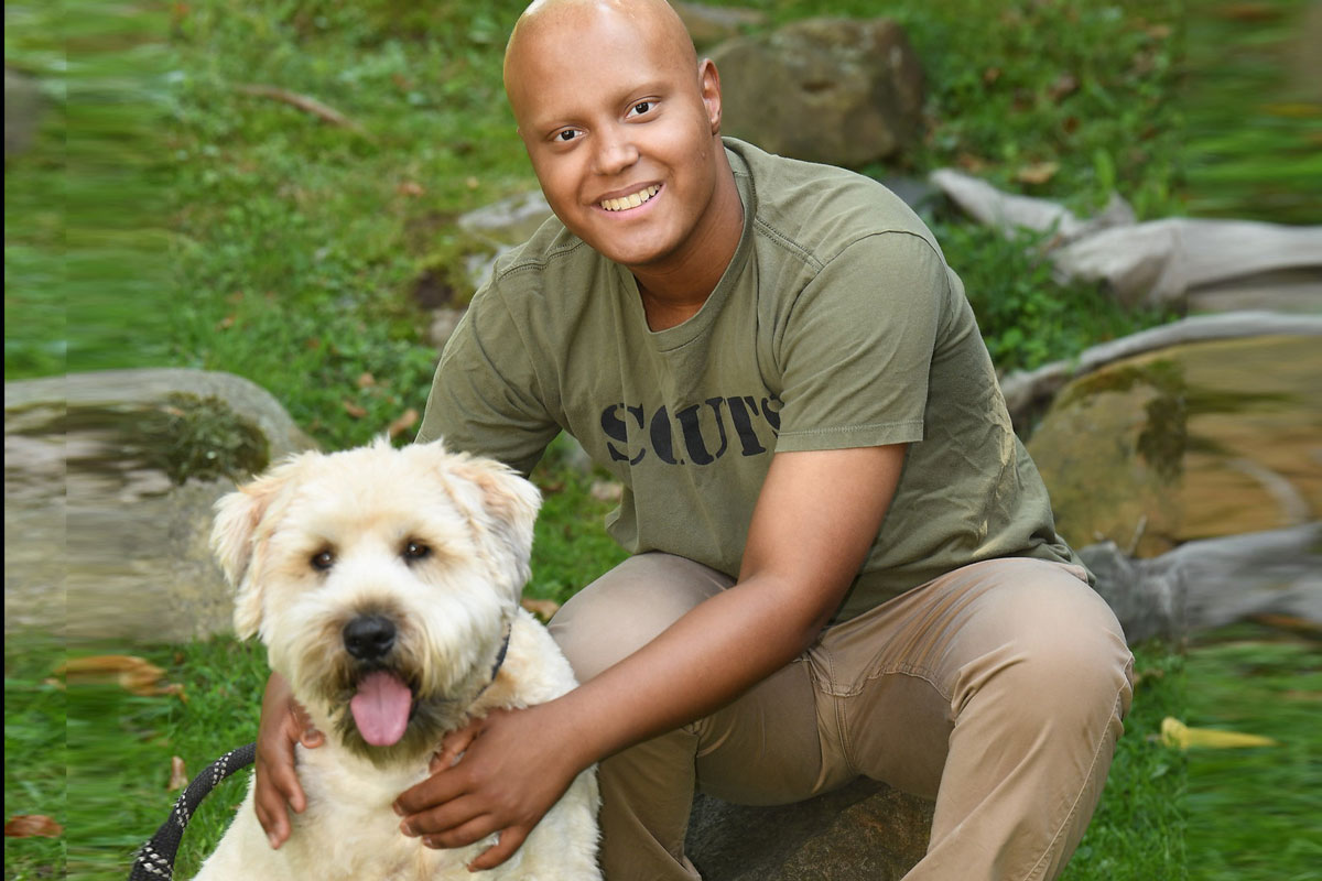 A young man who was treated at MSK poses with his dog